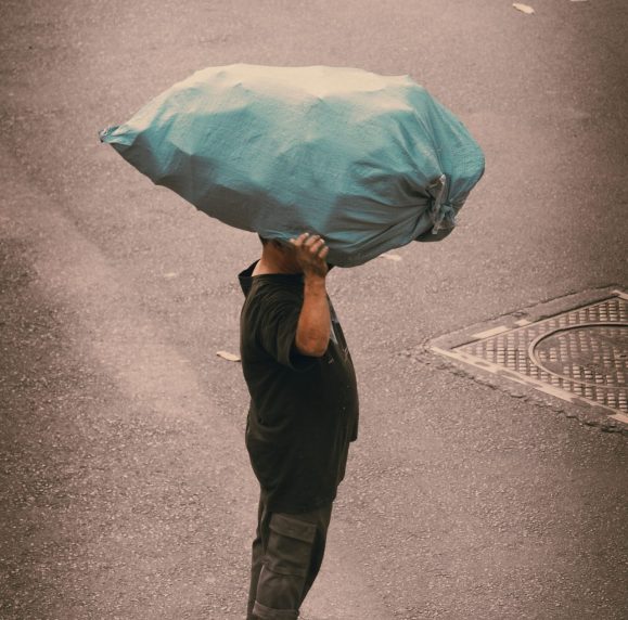 Man carrying large blue sack on his head