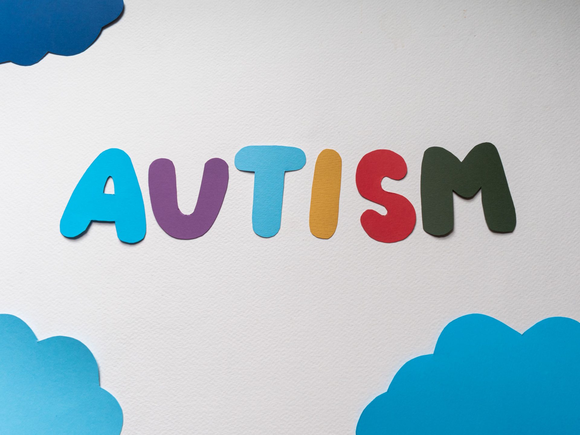 AUTISM spelt in coloured letters with blue clouds on edges