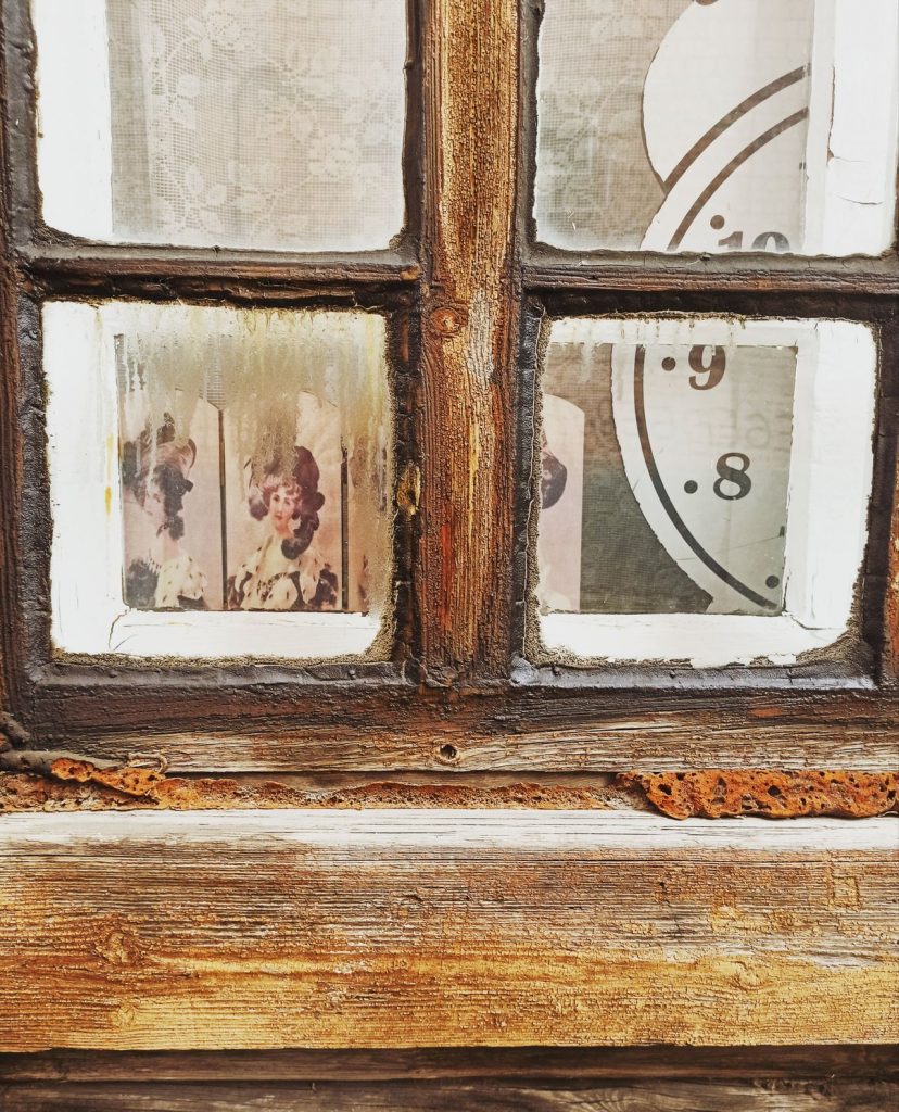 Wooden window with clock and picture on the inside.