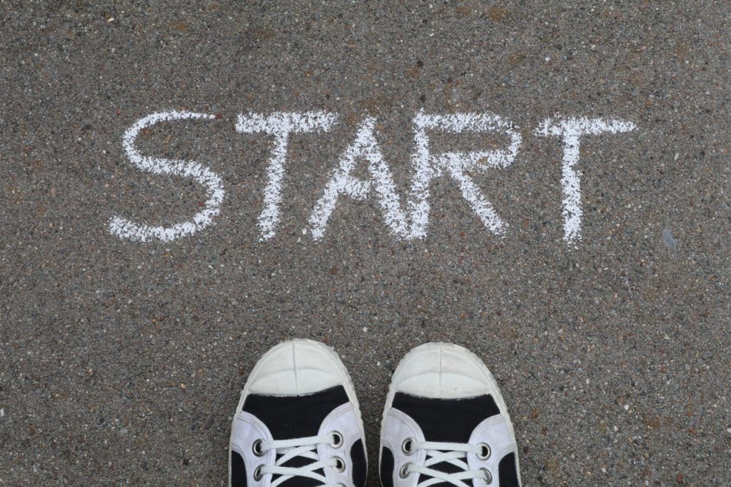 Start written on floor in chalk with pair of trainers beneath