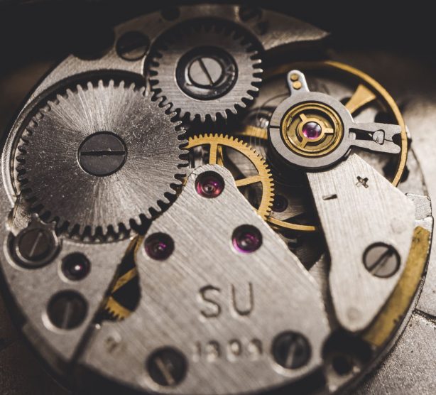 Detailed view of metal gears and components in a clock, highlighting precision engineering.