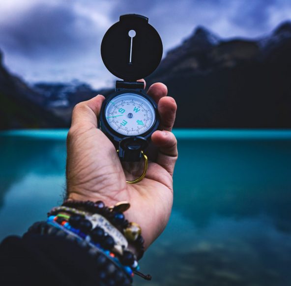 Man's hand holding compass with sea in background